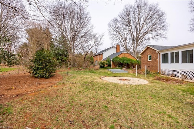 view of yard featuring a fire pit and a sunroom