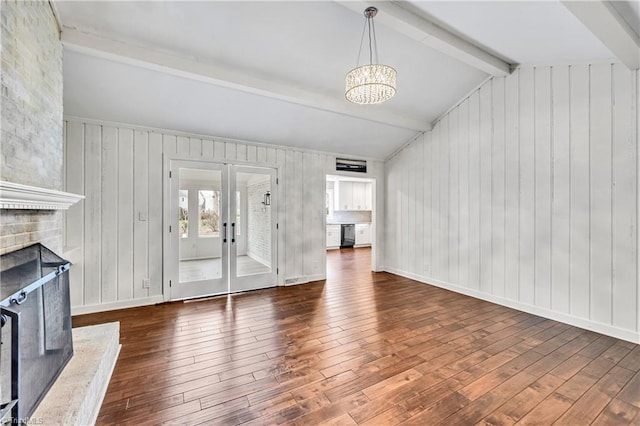 unfurnished living room featuring lofted ceiling with beams, french doors, wood-type flooring, and a large fireplace