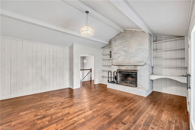 unfurnished living room with built in features, an inviting chandelier, vaulted ceiling with beams, a fireplace, and hardwood / wood-style flooring