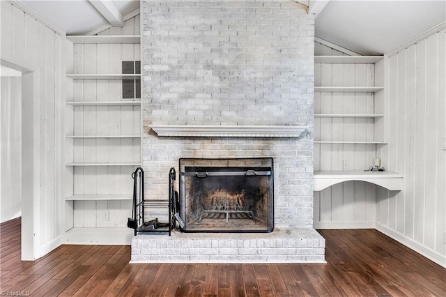 room details with wood finished floors, beamed ceiling, built in shelves, and a fireplace