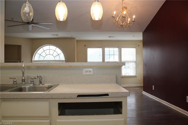 kitchen featuring sink, ceiling fan with notable chandelier, hanging light fixtures, and dark hardwood / wood-style floors