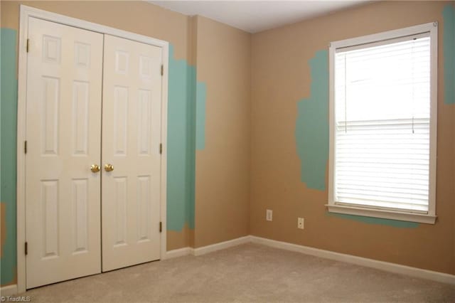 unfurnished bedroom featuring a closet and light colored carpet