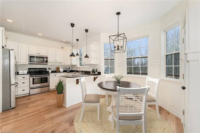 kitchen with decorative light fixtures, light wood finished floors, recessed lighting, and appliances with stainless steel finishes