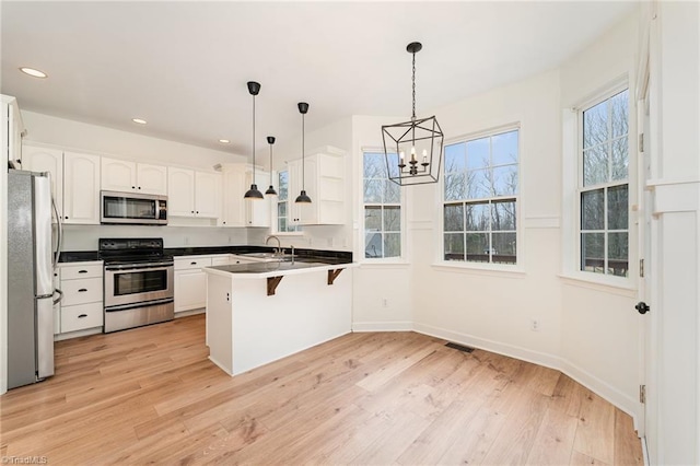 kitchen featuring a peninsula, a kitchen breakfast bar, light wood-style flooring, and stainless steel appliances