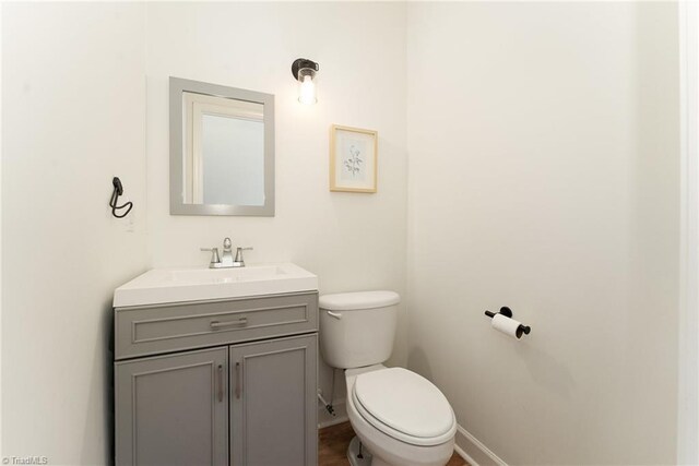 half bath with vanity, toilet, and baseboards