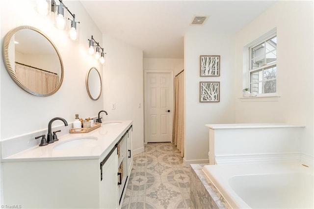 full bath with a sink, visible vents, tiled tub, and double vanity