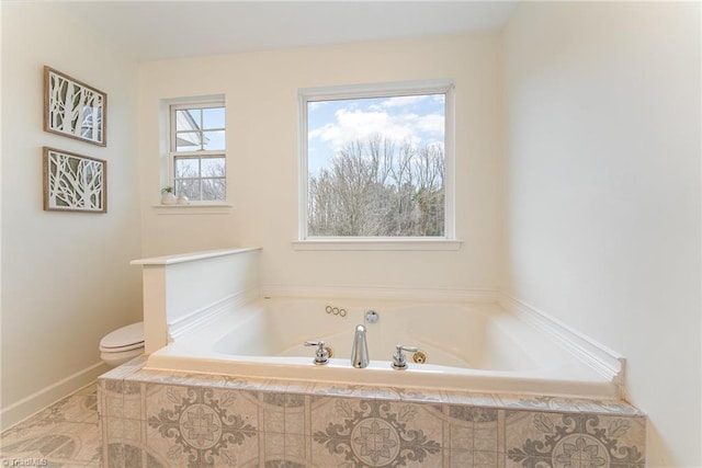 bathroom featuring baseboards, toilet, and a garden tub