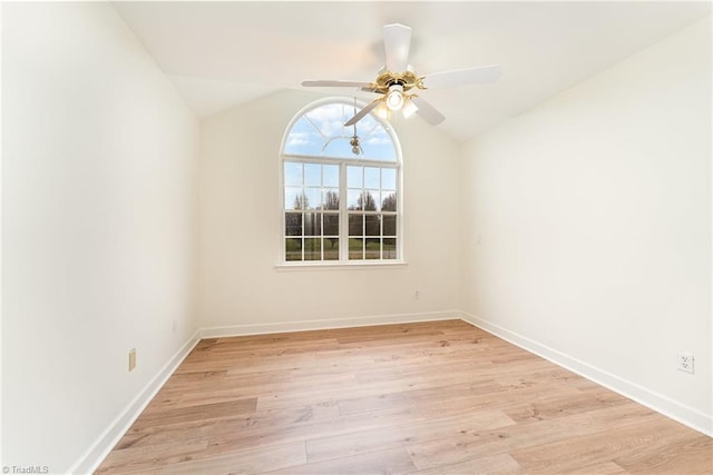 spare room featuring ceiling fan, baseboards, lofted ceiling, and light wood-style flooring