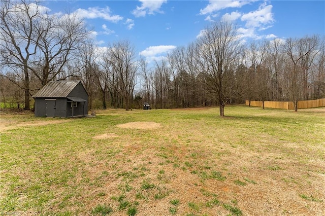 view of yard featuring an outbuilding, a storage shed, and fence