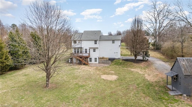 back of property featuring a wooden deck, driveway, a lawn, and stairs