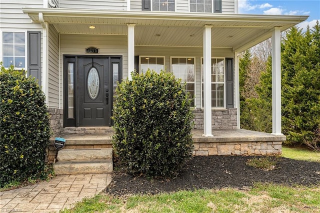 doorway to property with stone siding and covered porch