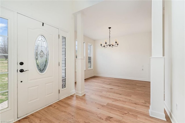 foyer entrance with light wood-style flooring, a notable chandelier, and baseboards