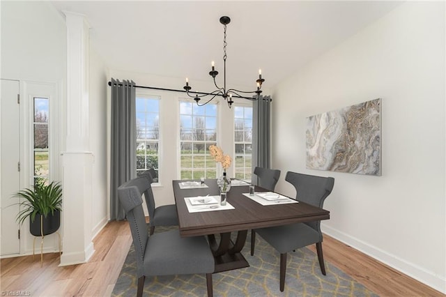 dining area featuring baseboards, a chandelier, and light wood finished floors