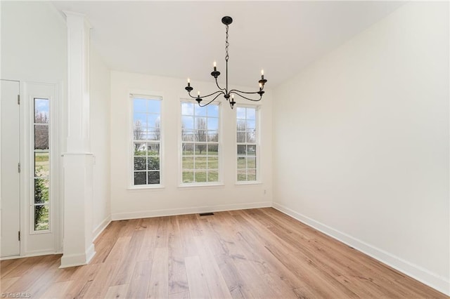 unfurnished dining area with light wood finished floors, visible vents, baseboards, a chandelier, and decorative columns