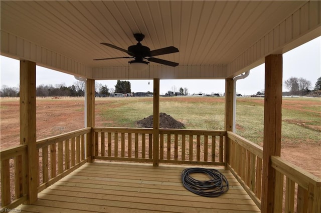 wooden deck with a ceiling fan, a rural view, and a yard