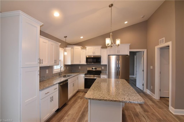 kitchen featuring a center island, stainless steel appliances, visible vents, white cabinetry, and a sink