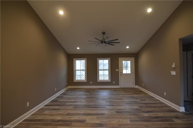 spare room with baseboards, vaulted ceiling, dark wood-type flooring, and recessed lighting