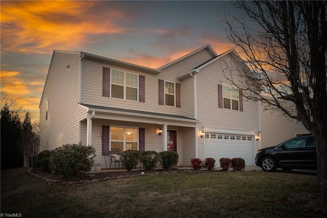 traditional-style home featuring covered porch, driveway, a lawn, and an attached garage