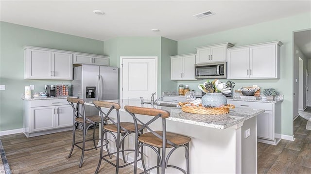 152 Rose Wind Way, Mayodan, NC 27027 - kitchen featuring stainless steel appliances, dark wood-type flooring, white cabinets, light stone countertops, and a center island with sink