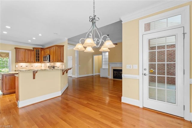 5080 Century Oaks Ln, Winston-Salem, NC 27106 - kitchen featuring stainless steel microwave, brown cabinetry, a breakfast bar area, ornamental molding, and a chandelier