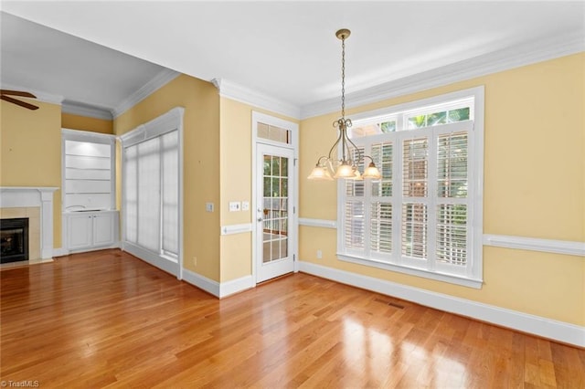 5080 Century Oaks Ln, Winston-Salem, NC 27106 - unfurnished dining area with wood finished floors, a chandelier, baseboards, ornamental molding, and a tiled fireplace