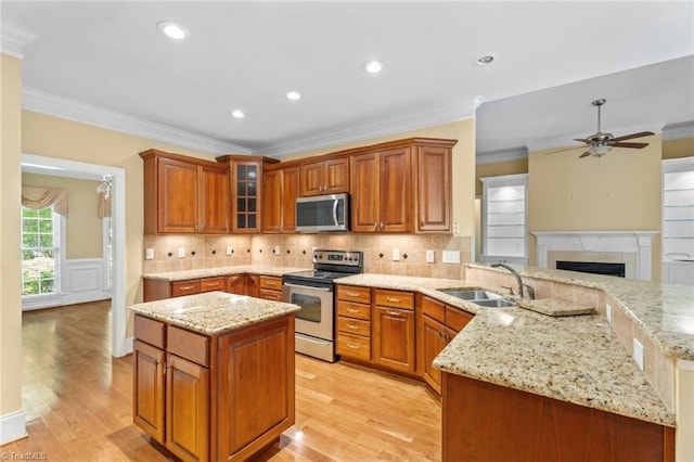 5080 Century Oaks Ln, Winston-Salem, NC 27106 - kitchen featuring appliances with stainless steel finishes, a sink, a peninsula, light stone counters, and light wood-style flooring