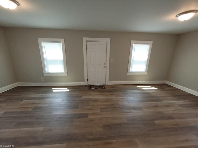 spare room featuring plenty of natural light, baseboards, and wood finished floors