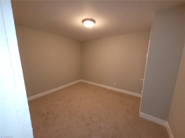 unfurnished room featuring baseboards and light colored carpet