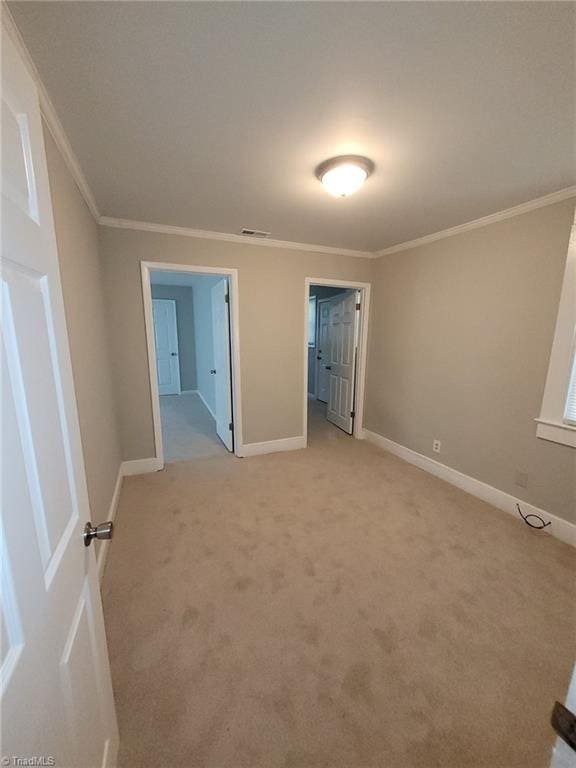 unfurnished bedroom with ensuite bathroom, light colored carpet, and crown molding