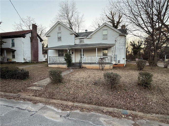 view of front of home featuring covered porch and a chimney