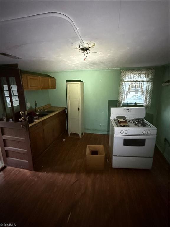 kitchen with dark wood-type flooring, white gas range, and a sink