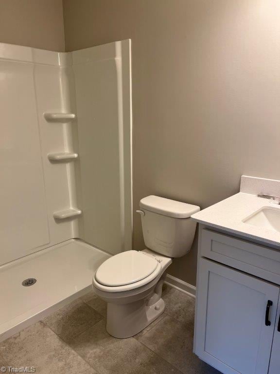 bathroom with walk in shower, vanity, tile patterned floors, and toilet