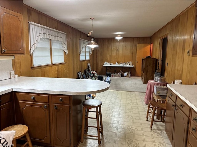 kitchen with pendant lighting, a kitchen breakfast bar, and wood walls