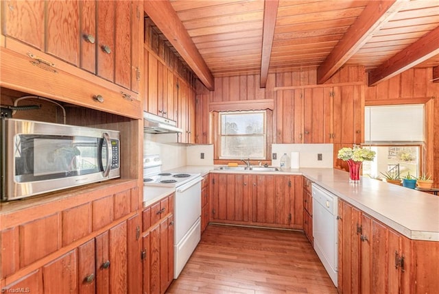 kitchen with white appliances, sink, light wood-type flooring, beamed ceiling, and kitchen peninsula