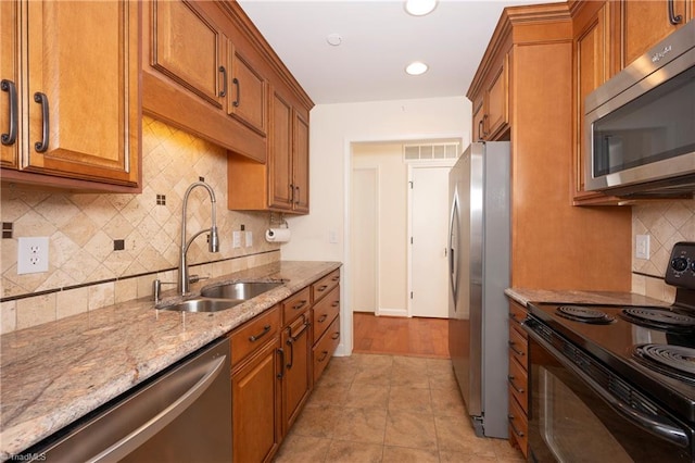 kitchen with light stone countertops, stainless steel appliances, tasteful backsplash, sink, and light tile patterned floors