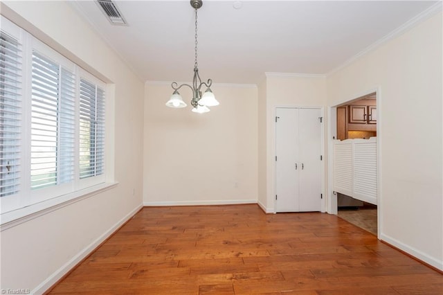 unfurnished room with ornamental molding, a notable chandelier, and hardwood / wood-style floors