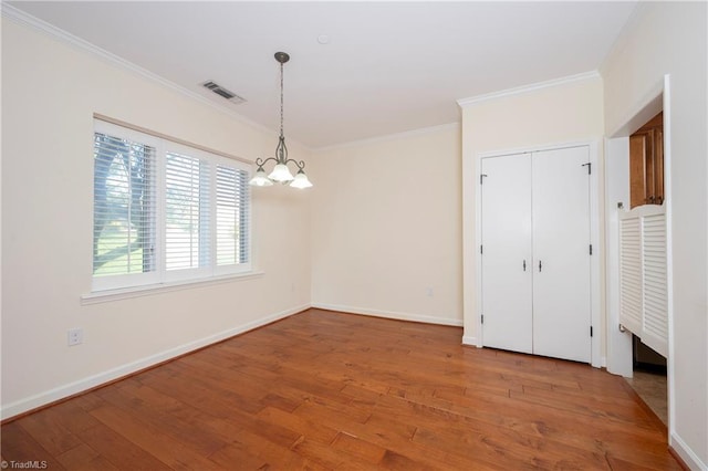 unfurnished dining area with crown molding, a chandelier, and hardwood / wood-style flooring