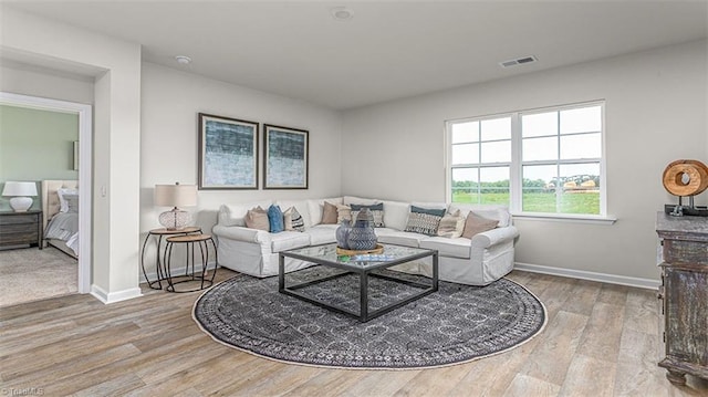 living room with light wood-style flooring, visible vents, and baseboards