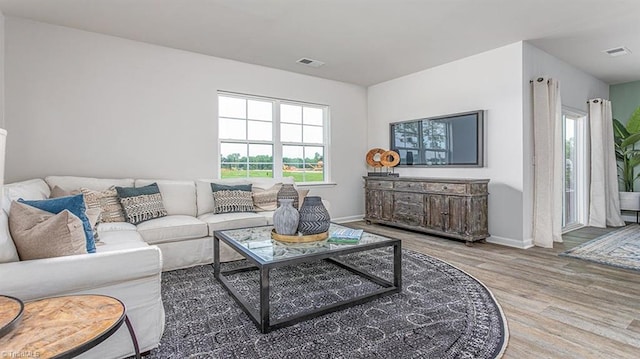 living room with a wealth of natural light, visible vents, and wood finished floors