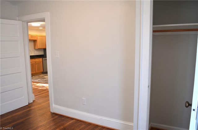 unfurnished bedroom with dark wood-type flooring, a closet, and baseboards