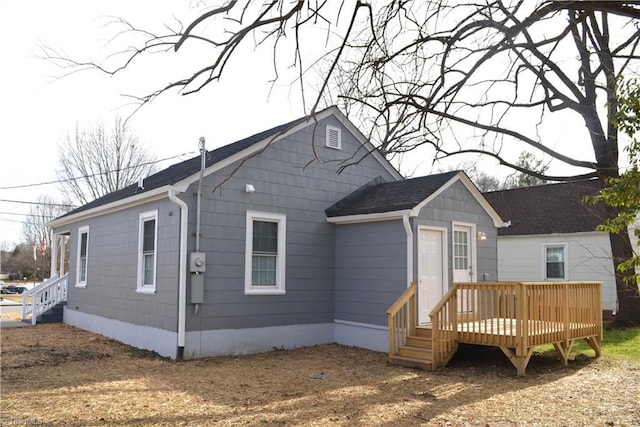 back of house featuring a shingled roof and a deck