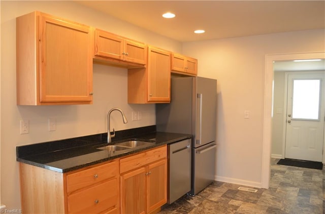 kitchen featuring baseboards, recessed lighting, dark stone counters, stainless steel dishwasher, and a sink