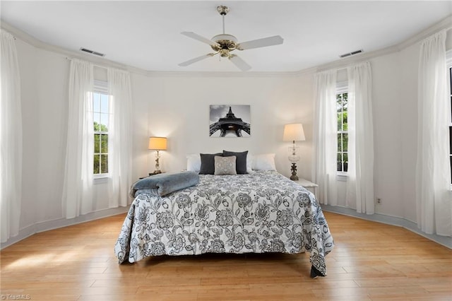 bedroom featuring light wood-style flooring, visible vents, and multiple windows