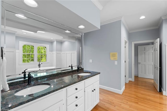 bathroom with ornamental molding, a sink, and wood finished floors