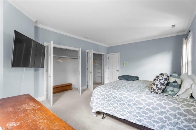 bedroom with light colored carpet, two closets, visible vents, and ornamental molding