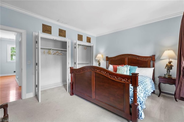 carpeted bedroom with baseboards, ornamental molding, a closet, and visible vents