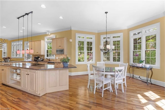 kitchen featuring baseboards, ornamental molding, light wood-style flooring, and stainless steel microwave