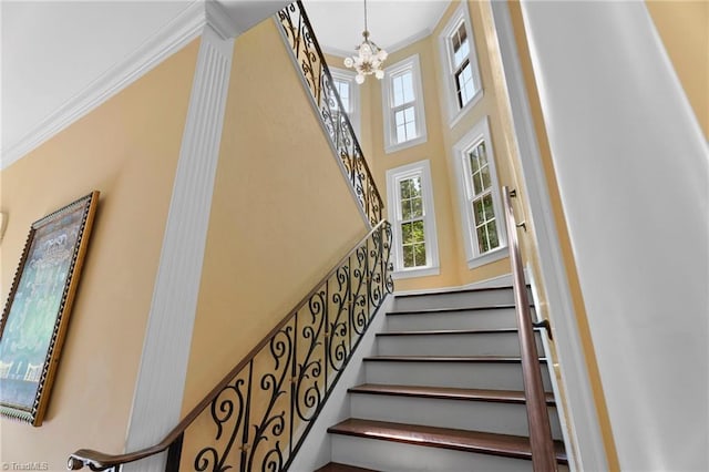 stairs with crown molding, a chandelier, and a high ceiling