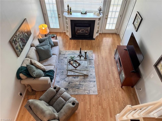 living room with baseboards, wood finished floors, and a fireplace with flush hearth