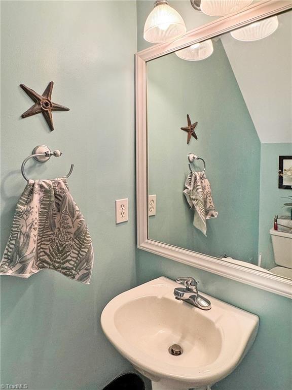 bathroom featuring a sink and lofted ceiling